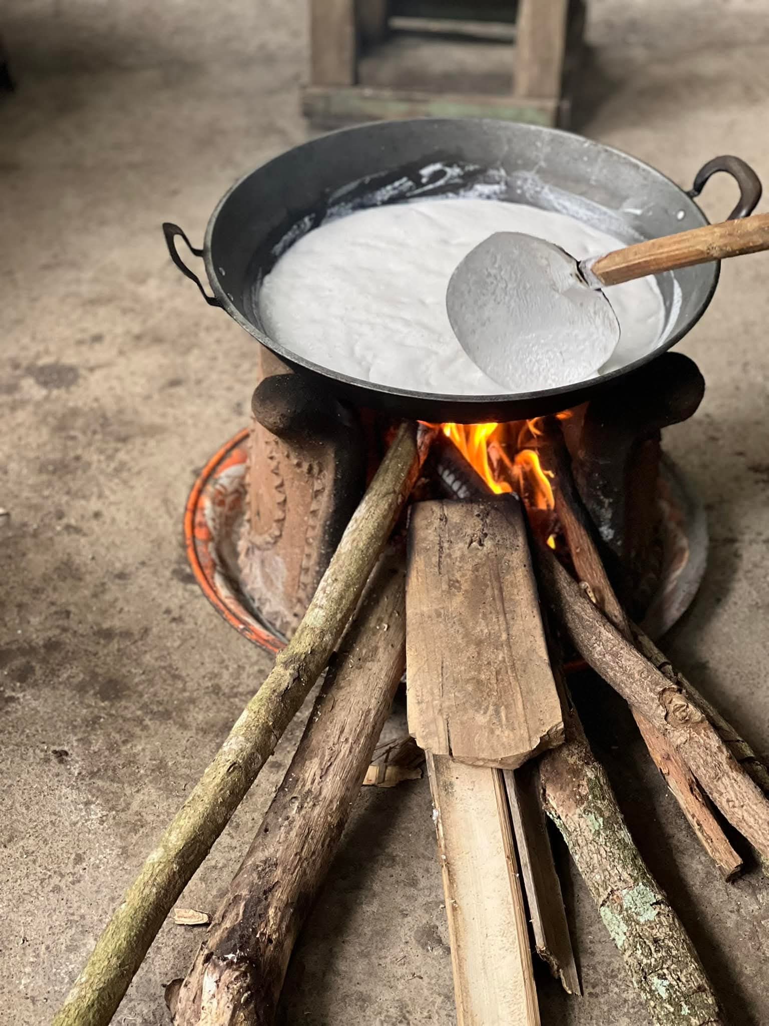 Local woman demonstrating traditional coconut oil making process in Lombok village workshop.