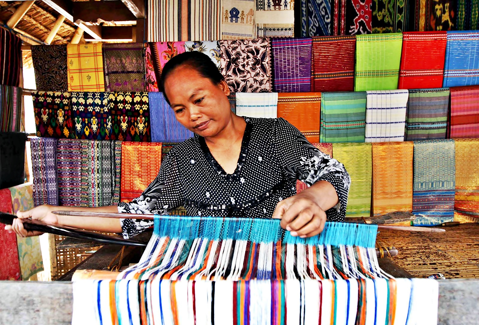 Traditional hand weaving process at Lombok Pottery Studio with local artisan crafting textile